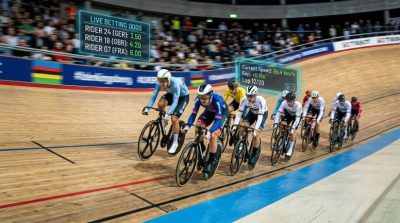 A velodrome cycling race with riders leaning sharply on a curved track
